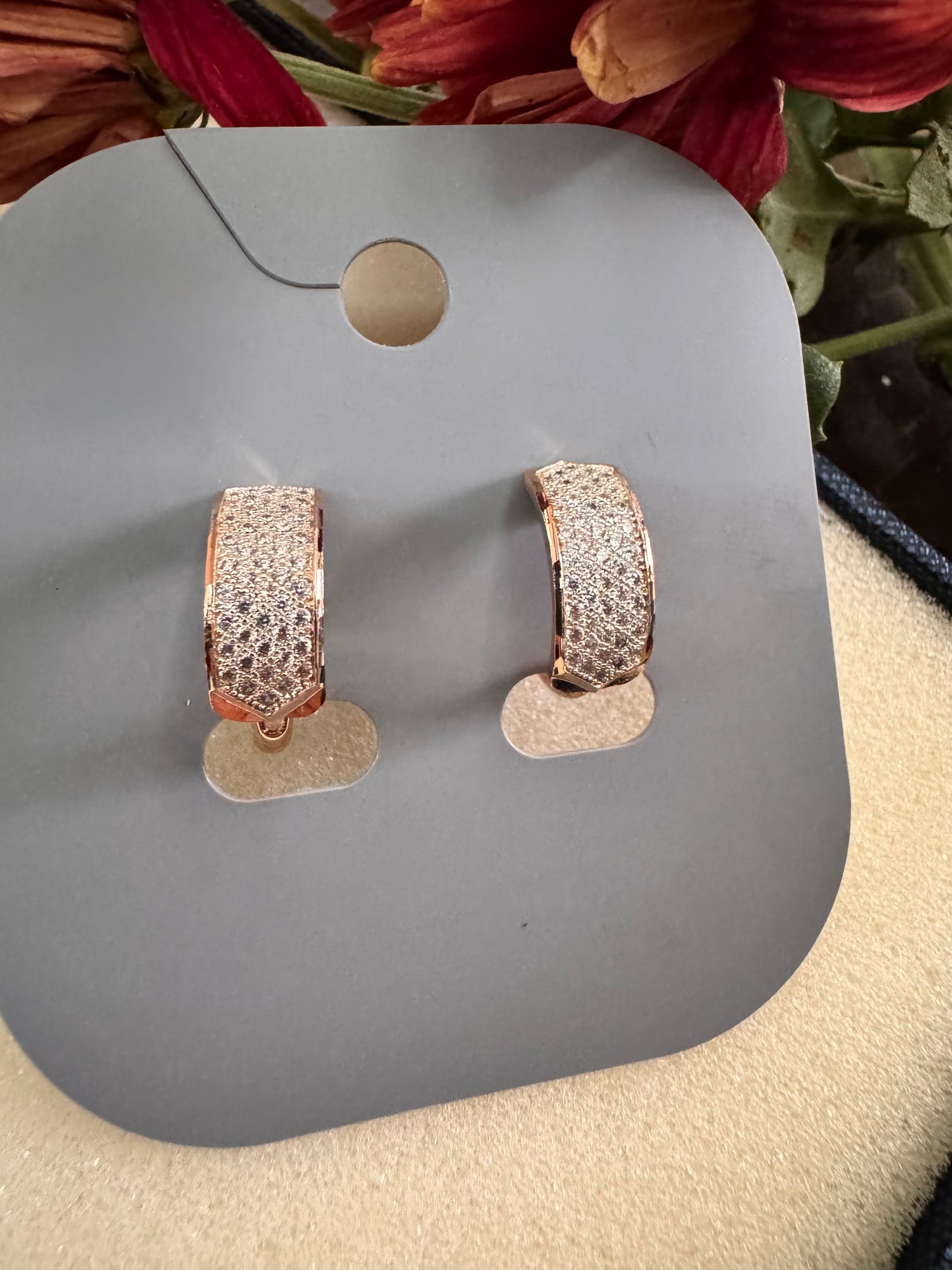 Rose gold hoop earrings on a gray display card with flowers in the background. Erica Jewelry India Dainty Everyday Minimal Gold Silver Jewelry